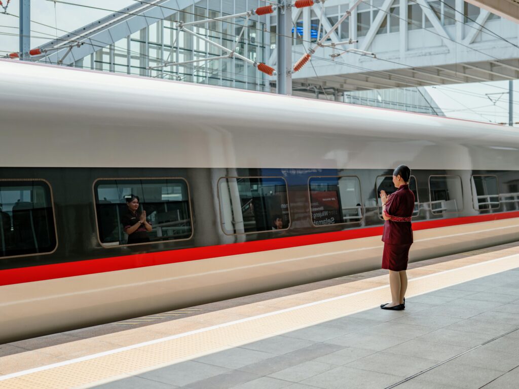 Home A sleek bullet train at a Jakarta station with a conductor in uniform. Modern transportation captured.